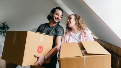 two people holding moving boxes in their new rented apartment