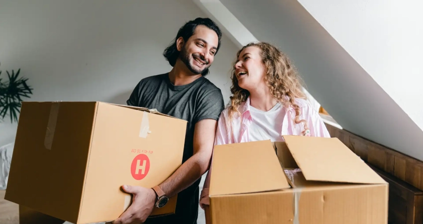 two people holding moving boxes in their new rented apartment