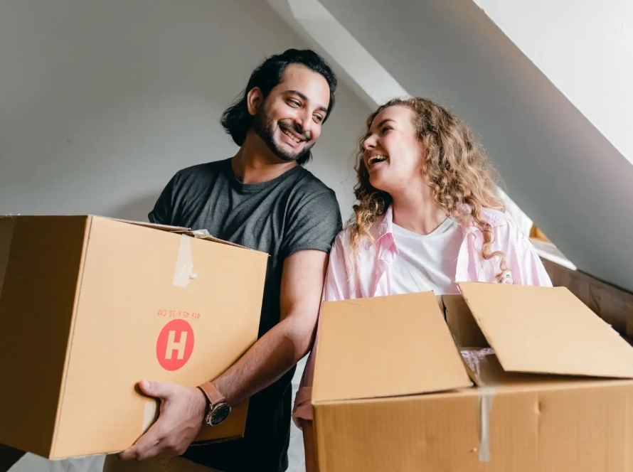 two people holding moving boxes in their new rented apartment